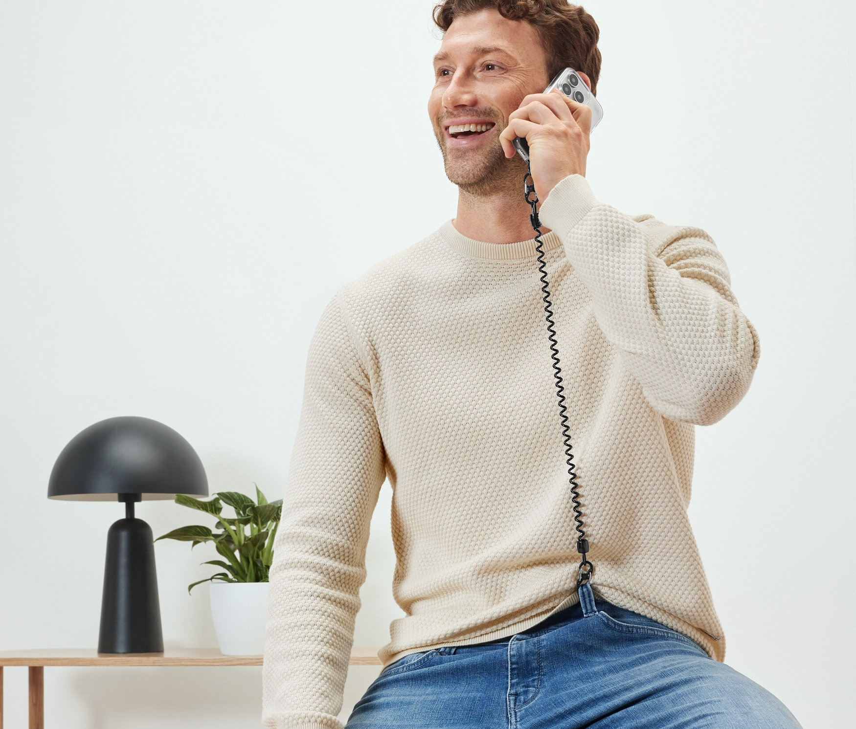 Un homme est assis et téléphone avec une chaîne de sécurité pour téléphone portable.