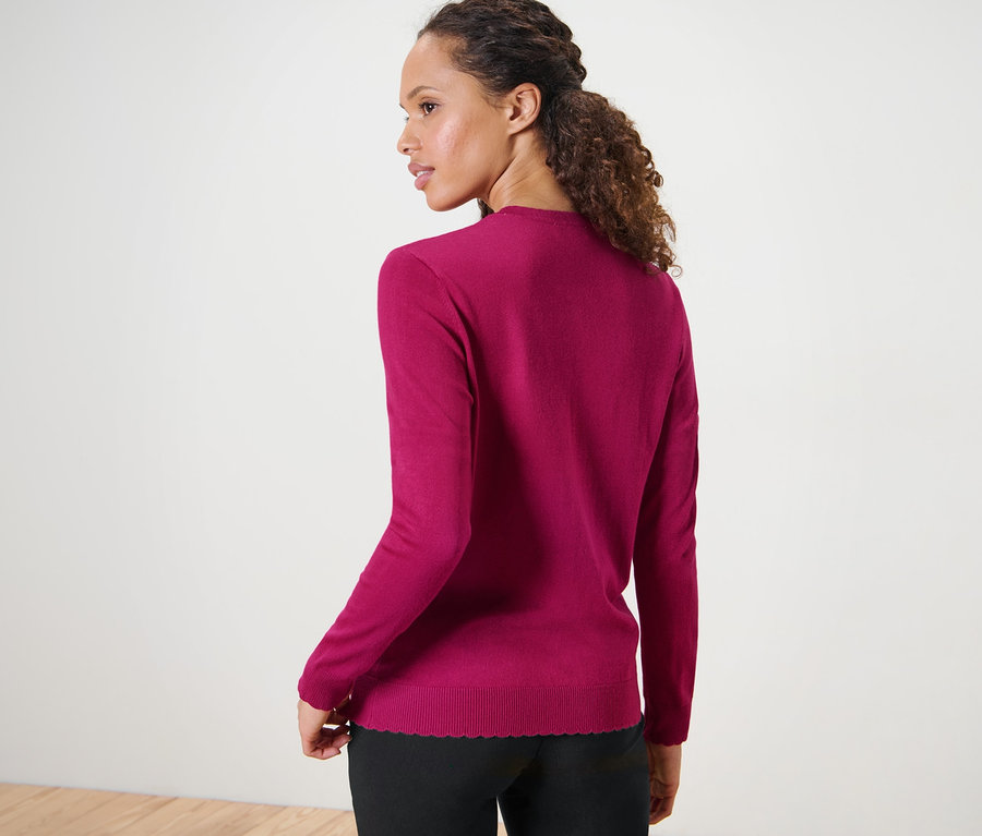 Femme portant un cardigan à maille fine avec bord ondulé.