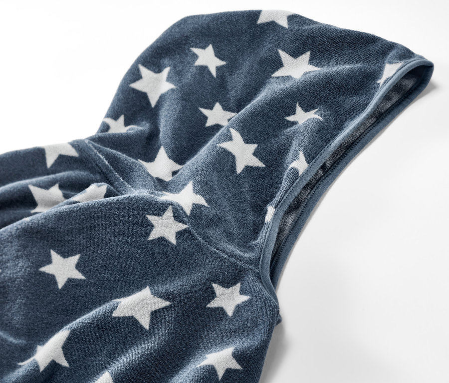 Gros plan sur un poncho en tissu éponge pour enfant avec capuche et motif étoiles.