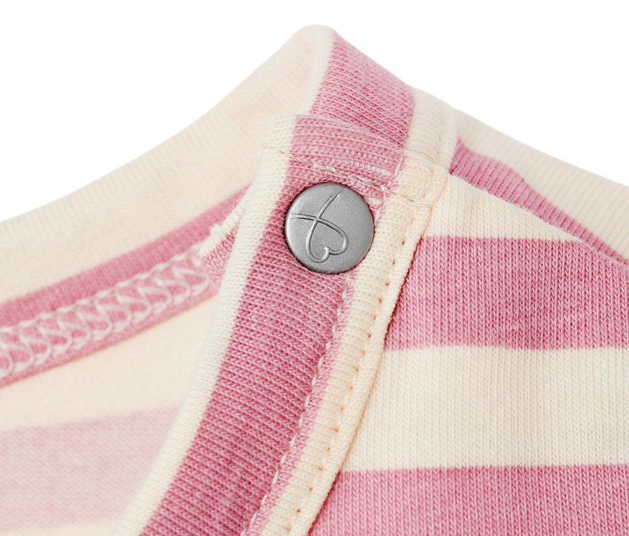 Gros plan sur une robe en jersey pour bébé rayée rose et crème, avec un bouton argenté en forme de cœur.