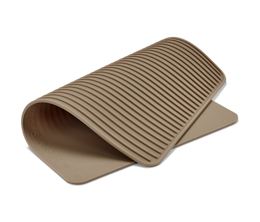 Un tapis de cuisson beige double face est partiellement enroulé sur un fond blanc.