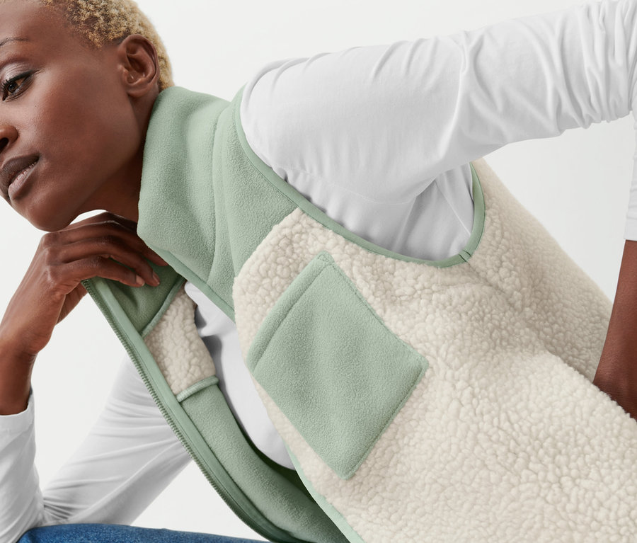 Femme posant dans un gilet sans manches en peluche beige et menthe.
