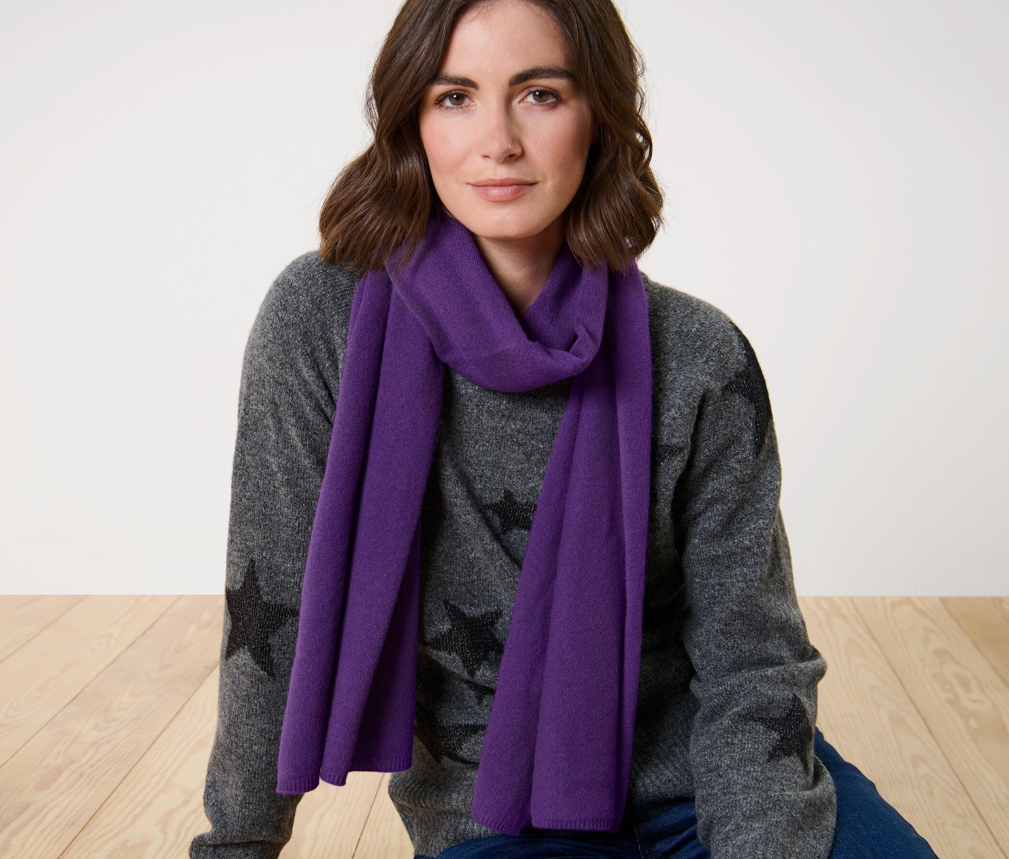 Femme portant une écharpe en cachemire tricoté violette.