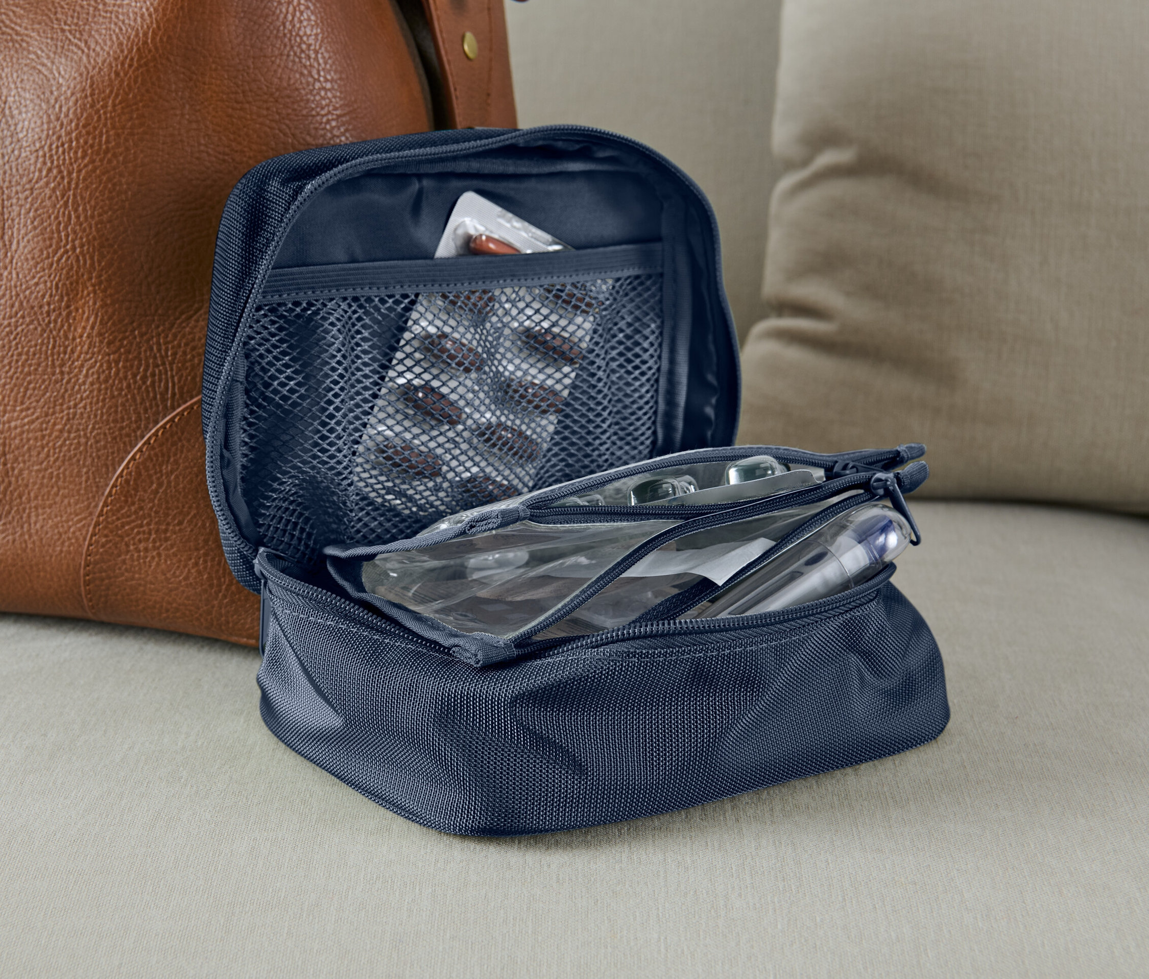 Trousse à pharmacie bleue ouverte à côté d'un sac en cuir marron.