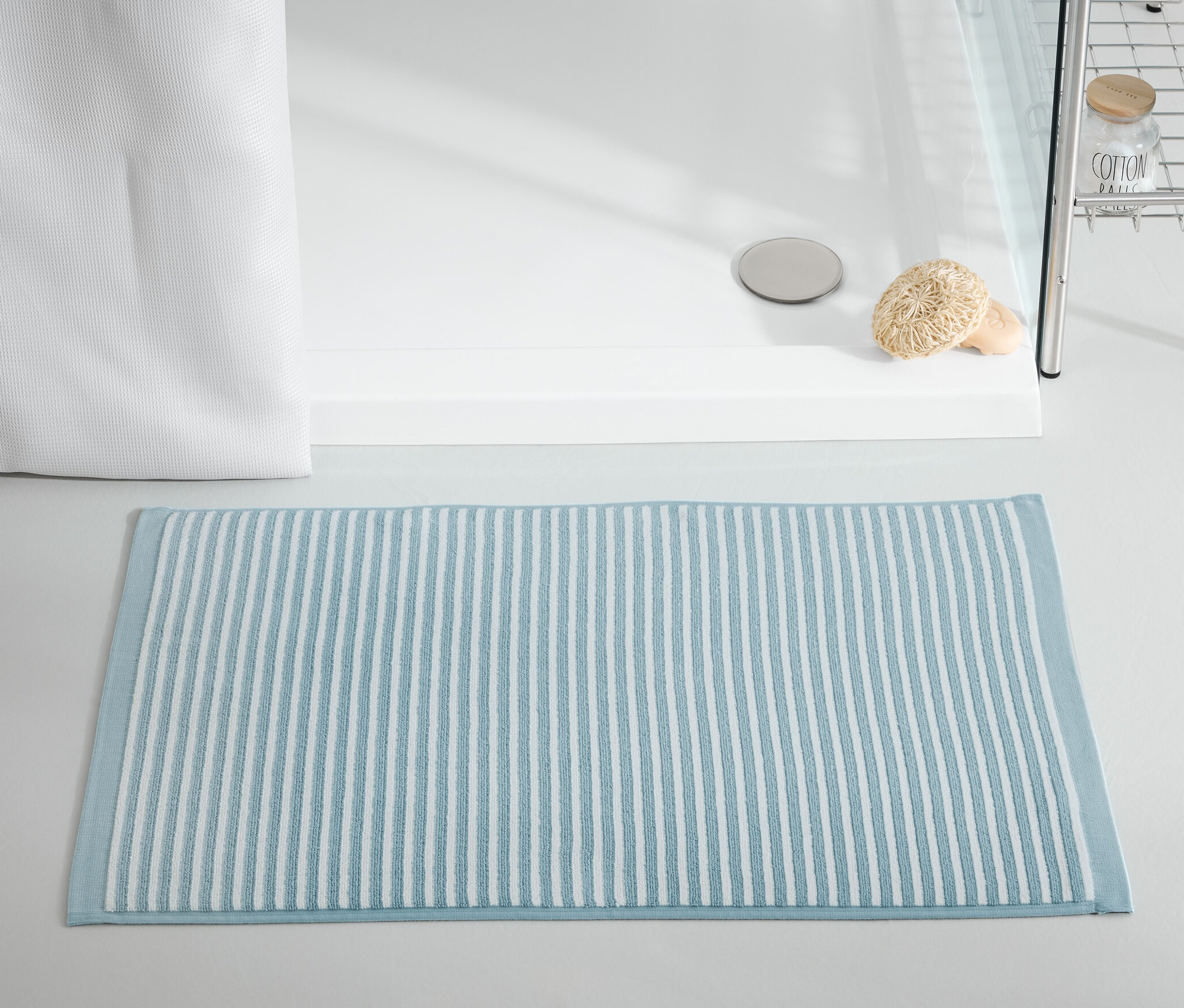 Un tapis de douche bleu est posé devant une cabine de douche.