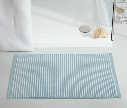 Un tapis de douche bleu est posé devant une cabine de douche.