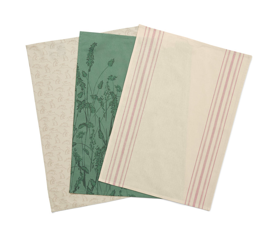 Trois linges de cuisine : un avec un motif de lapin, un avec un motif d'herbe verte et un avec des rayures roses.