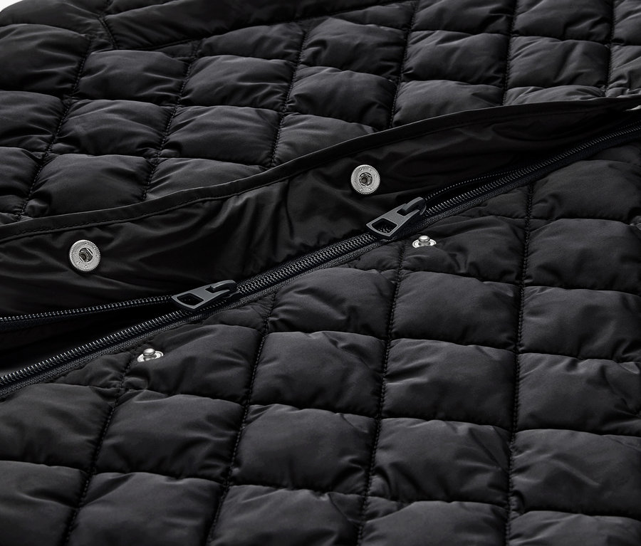Détail d'un long gilet matelassé noir avec capuche, avec fermeture éclair et boutons-pression.