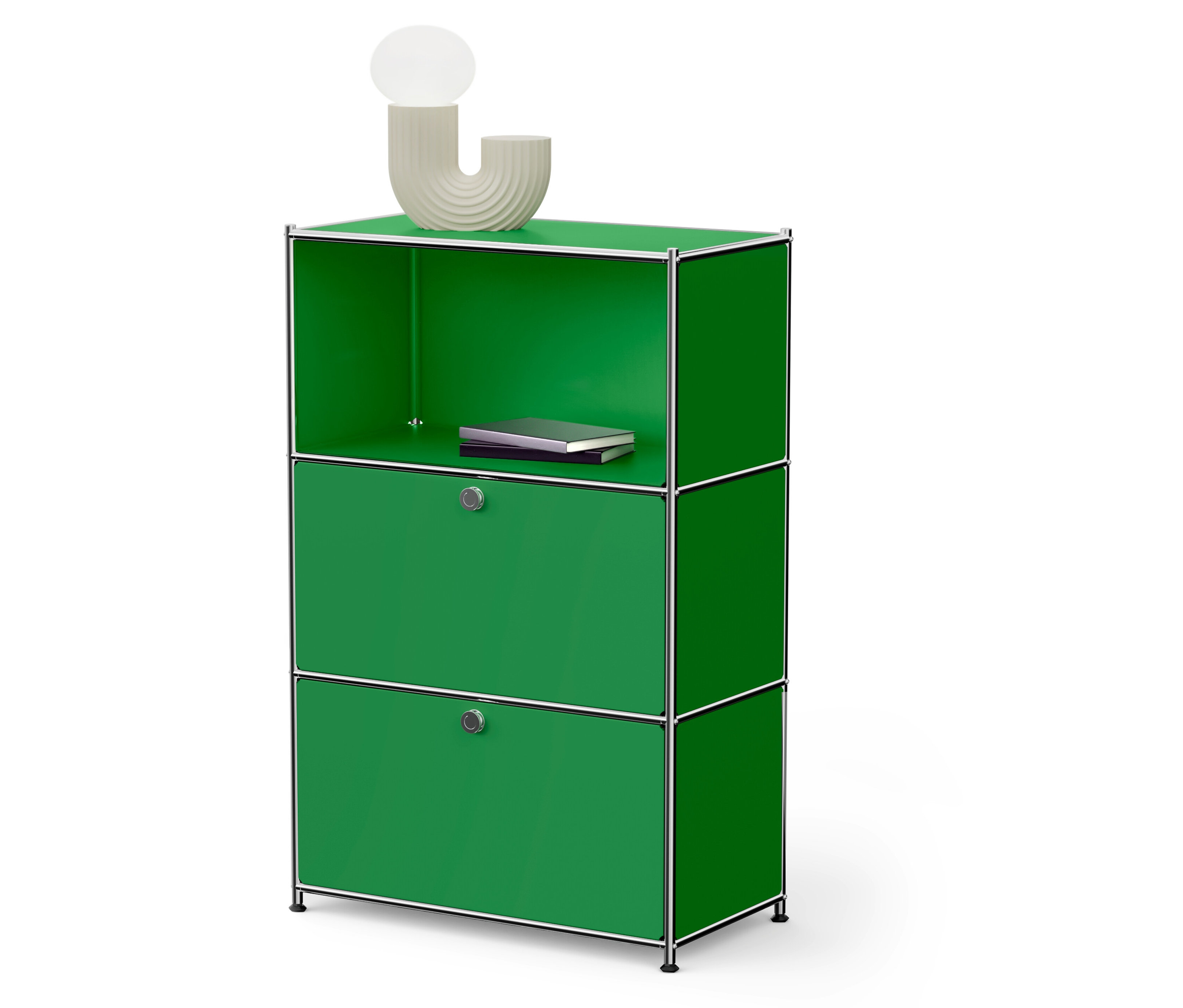 Un meuble de rangement modulaire vert avec deux portes et une étagère ouverte sur laquelle repose un livre. Une lampe est posée sur le dessus.