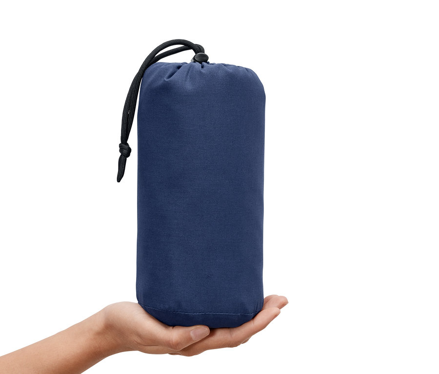 Une main tenant une doublure pour sac de couchage bleue avec cordon de serrage.