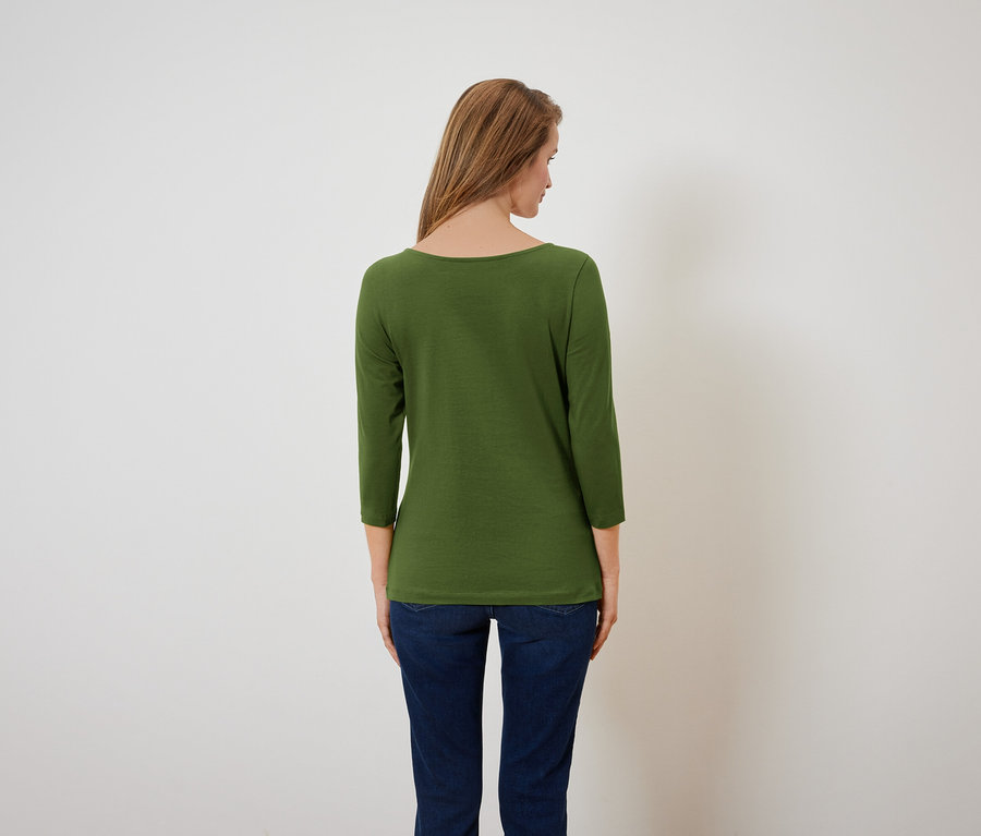 Une femme, vue de dos, porte un t-shirt vert à manches trois-quarts et un jean bleu.