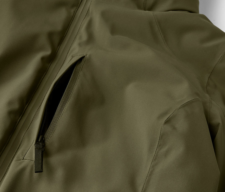 Détail d'une veste vert olive avec une poche zippée.
