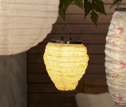 Trois petits lampions solaires suspendus à un arbre au-dessus d'une table et d'un banc.