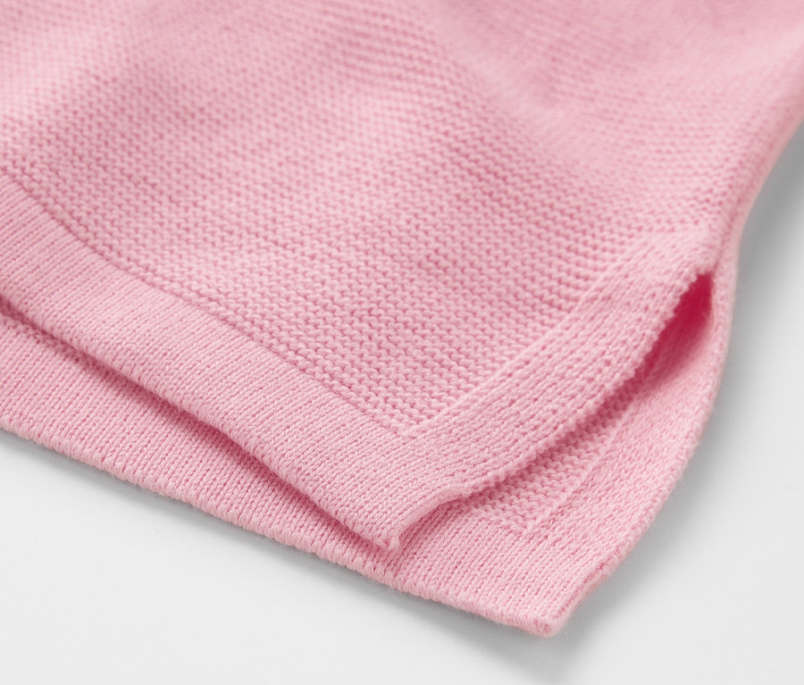 Gros plan sur un pull en maille rose.