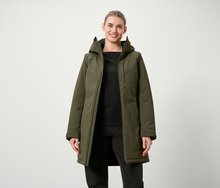 Femme posant en veste olive avec capuche et vêtements noirs.