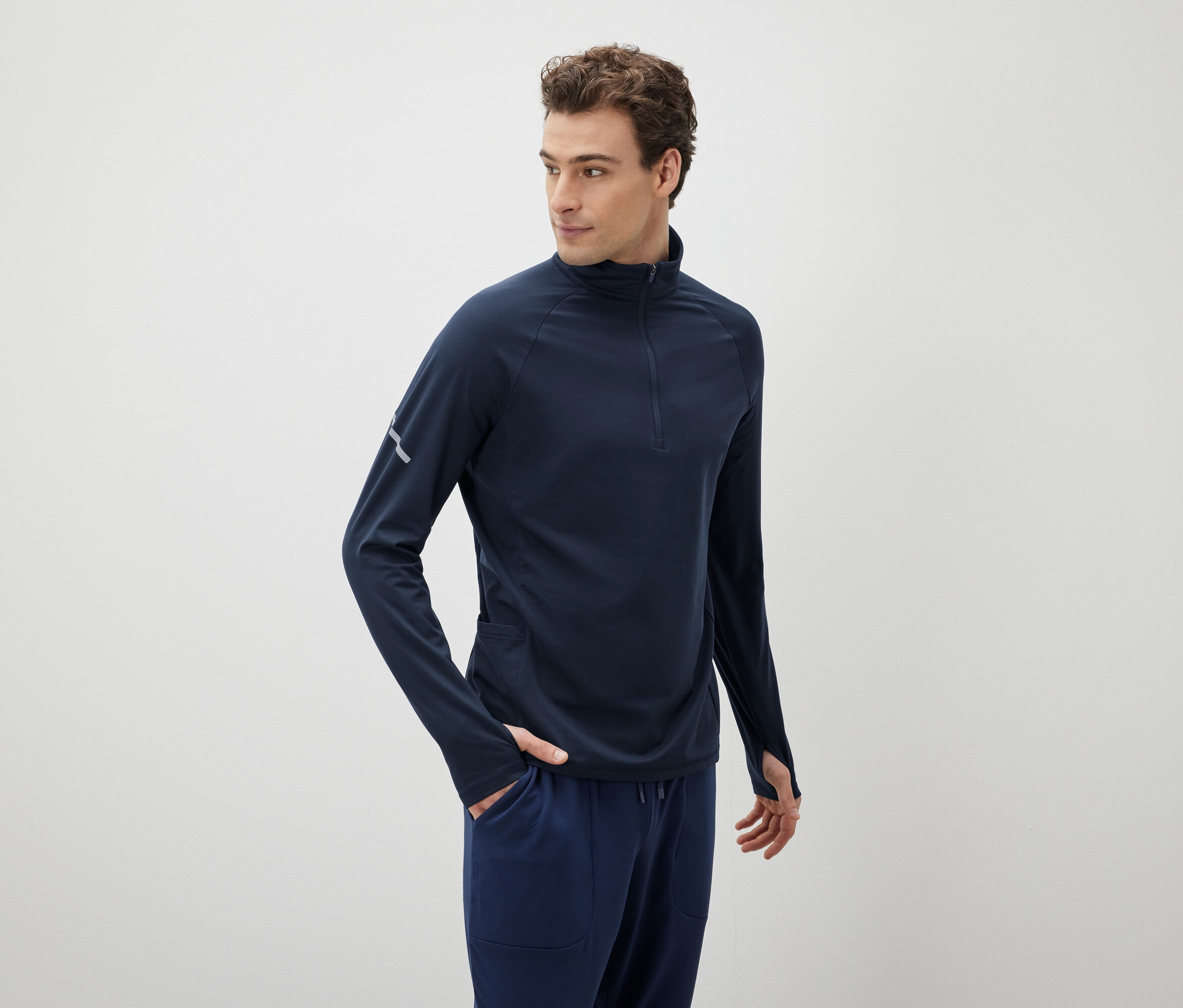 Homme portant un t-shirt de sport à manches longues bleu marine et un pantalon.