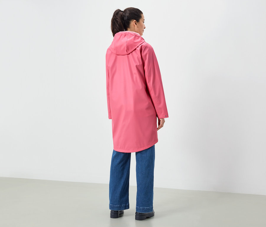Une femme vue de dos portant un imperméable rose à capuche et un jean bleu.