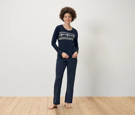 Une femme debout porte un pyjama bleu marine à motifs.