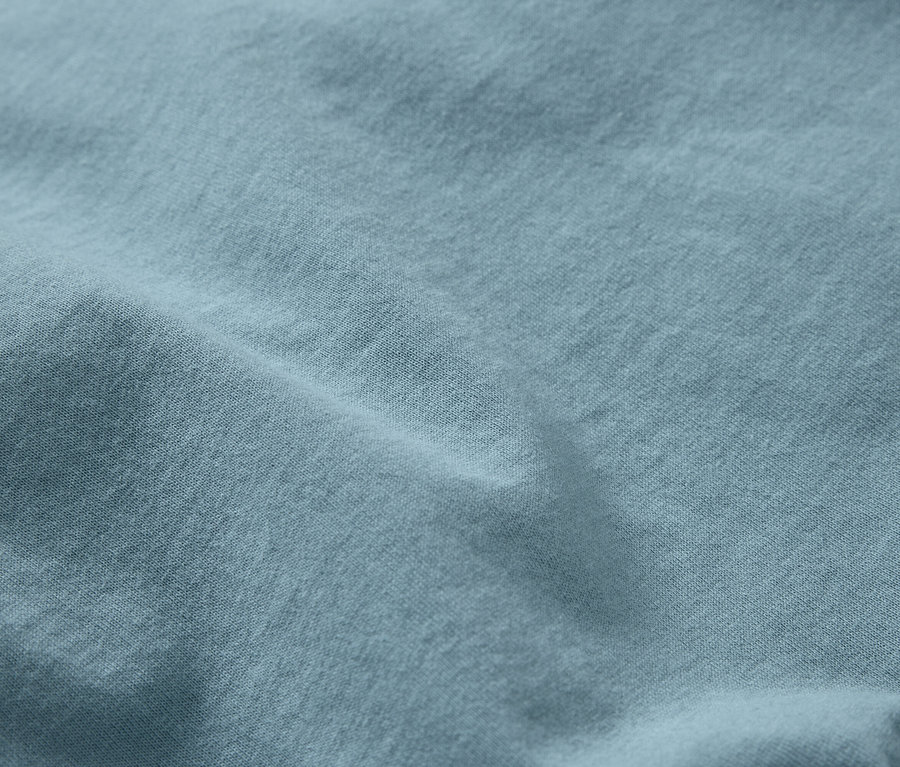 Gros plan d'un tissu bleu clair avec une texture fine et des plis.
