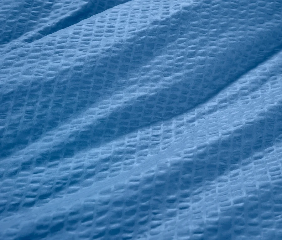 Gros plan d'une parure de lit en seersucker bleue.