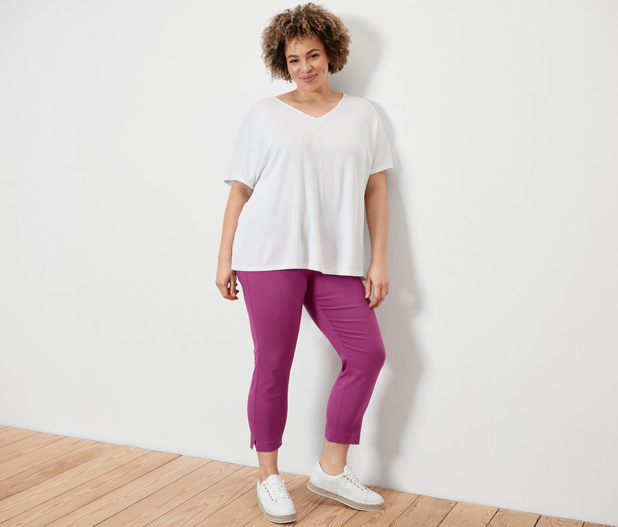 Femme posant en pantalon stretch 7/8, baies, et blouse structurée, blanc.