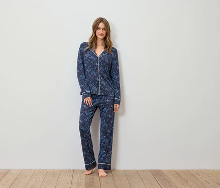 Une femme debout portant un pyjama bleu imprimé.