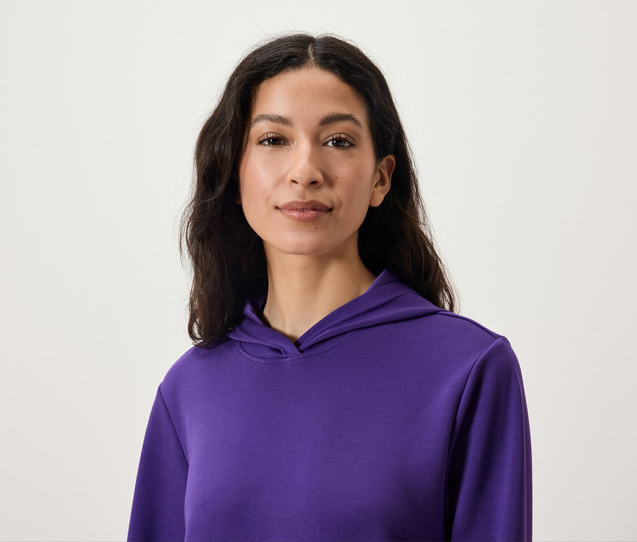 Portrait d'une femme aux cheveux foncés portant un sweat à capuche violet.