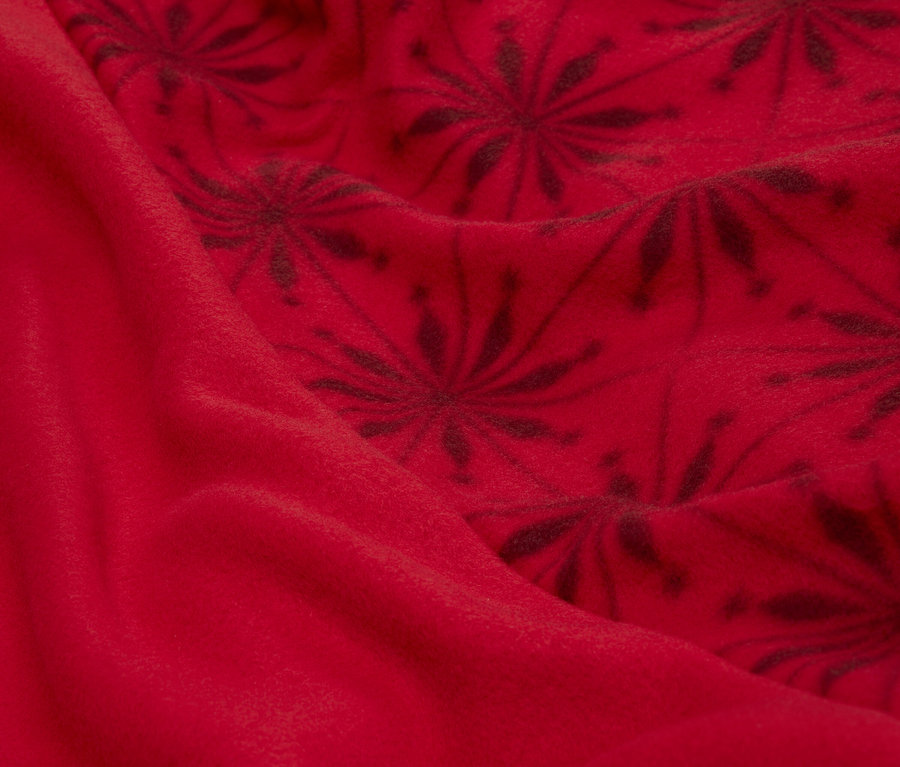 Gros plan d'un tissu rouge avec un motif floral foncé.