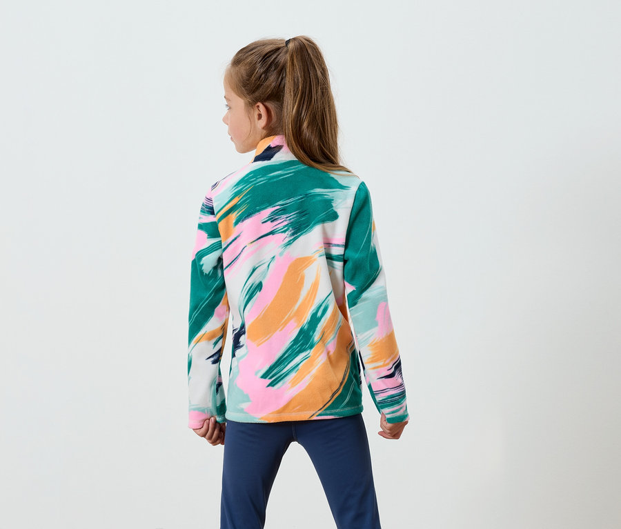 Une fille aux cheveux bruns attachés en queue de cheval, vue de dos, porte un sweat-shirt à motifs de coups de pinceau verts, roses et oranges, ainsi qu'un pantalon bleu.