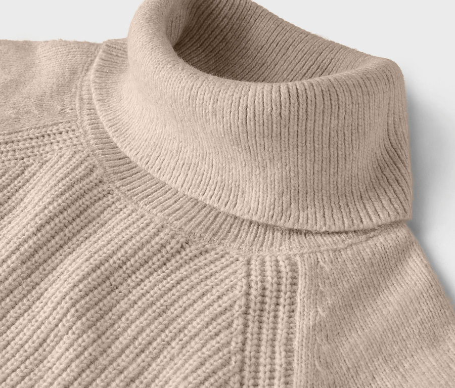 Gros plan d'un pull à col roulé beige avec une texture côtelée.