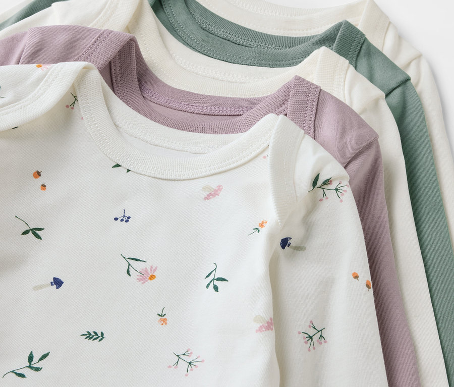 Gros plan sur cinq bodys pour bébés adaptables à la croissance en blanc, rose et vert.