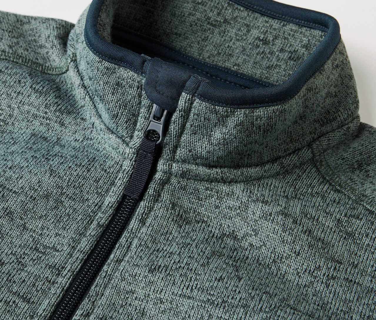 Détail d'une veste en maille polaire hybride pour enfant avec fermeture éclair.