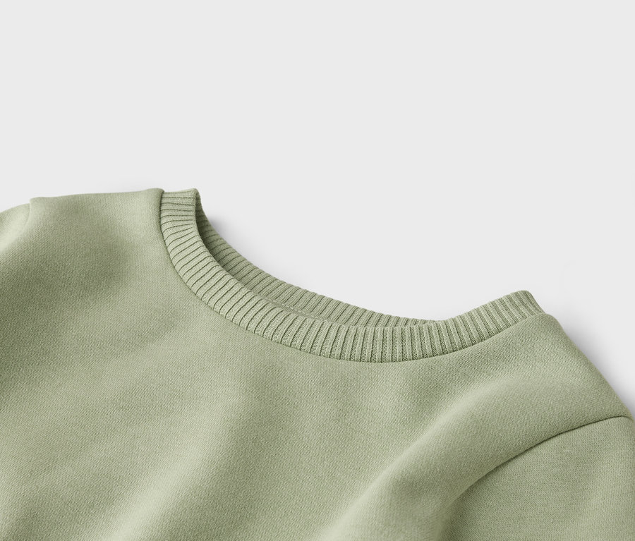 Gros plan du col rond côtelé d'un sweat-shirt vert clair.