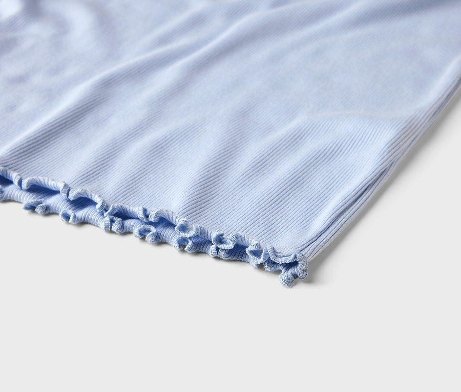 Gros plan d'un tissu côtelé bleu clair avec un ourlet à froufrous.