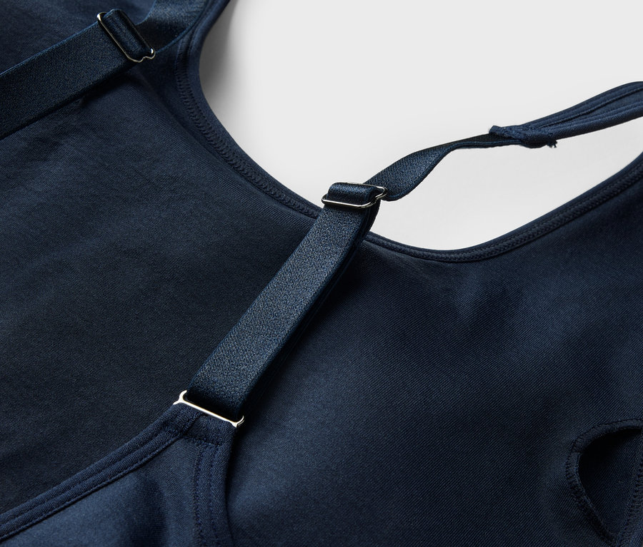 Gros plan d'un soutien-gorge bleu marine avec bretelles réglables et boucles argentées.