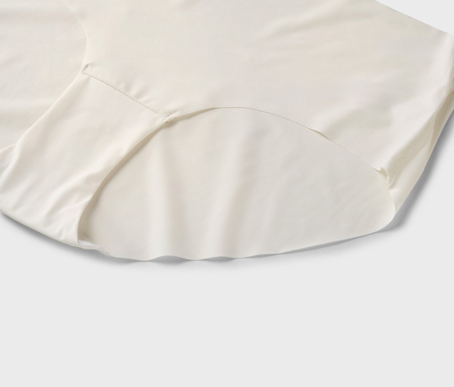 Gros plan d'une culotte couleur crème sur un fond gris clair.