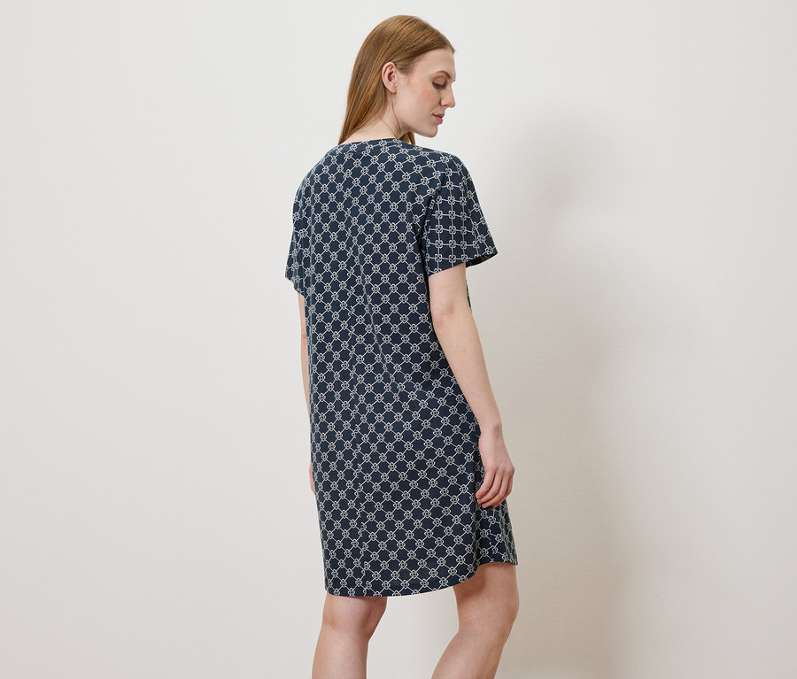Femme vue de dos portant une robe bleue avec un motif blanc.