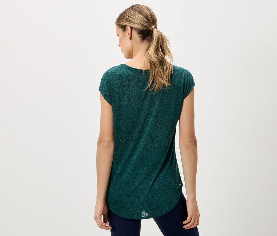Vue arrière d'une femme blonde portant un t-shirt vert et un pantalon bleu.
