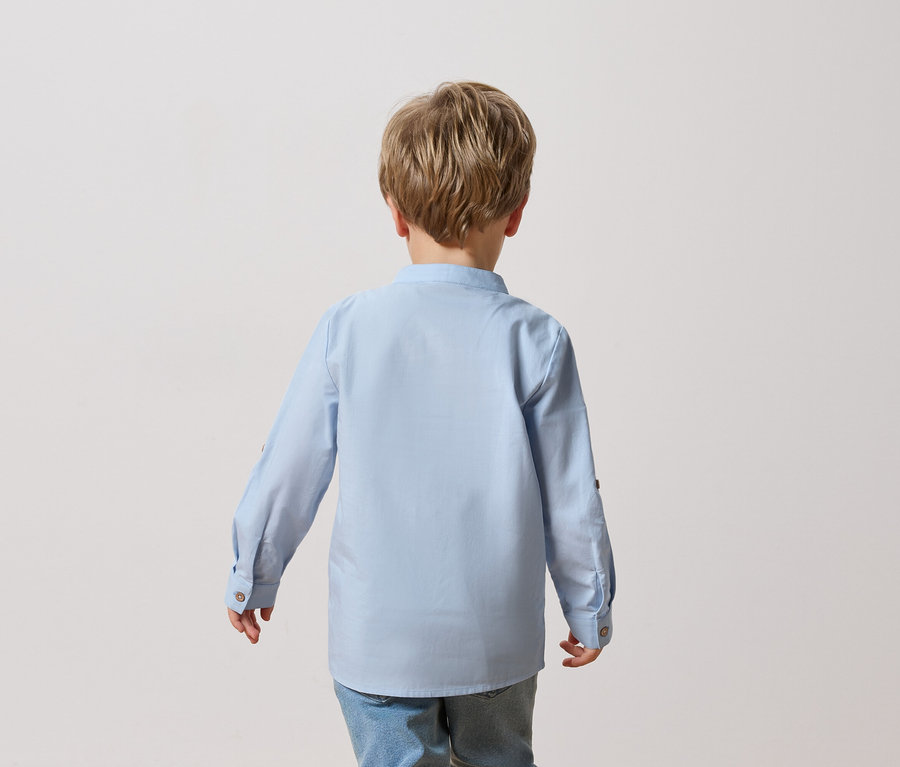 Vue arrière d'un enfant aux cheveux blonds portant une chemise bleu clair et un jean.