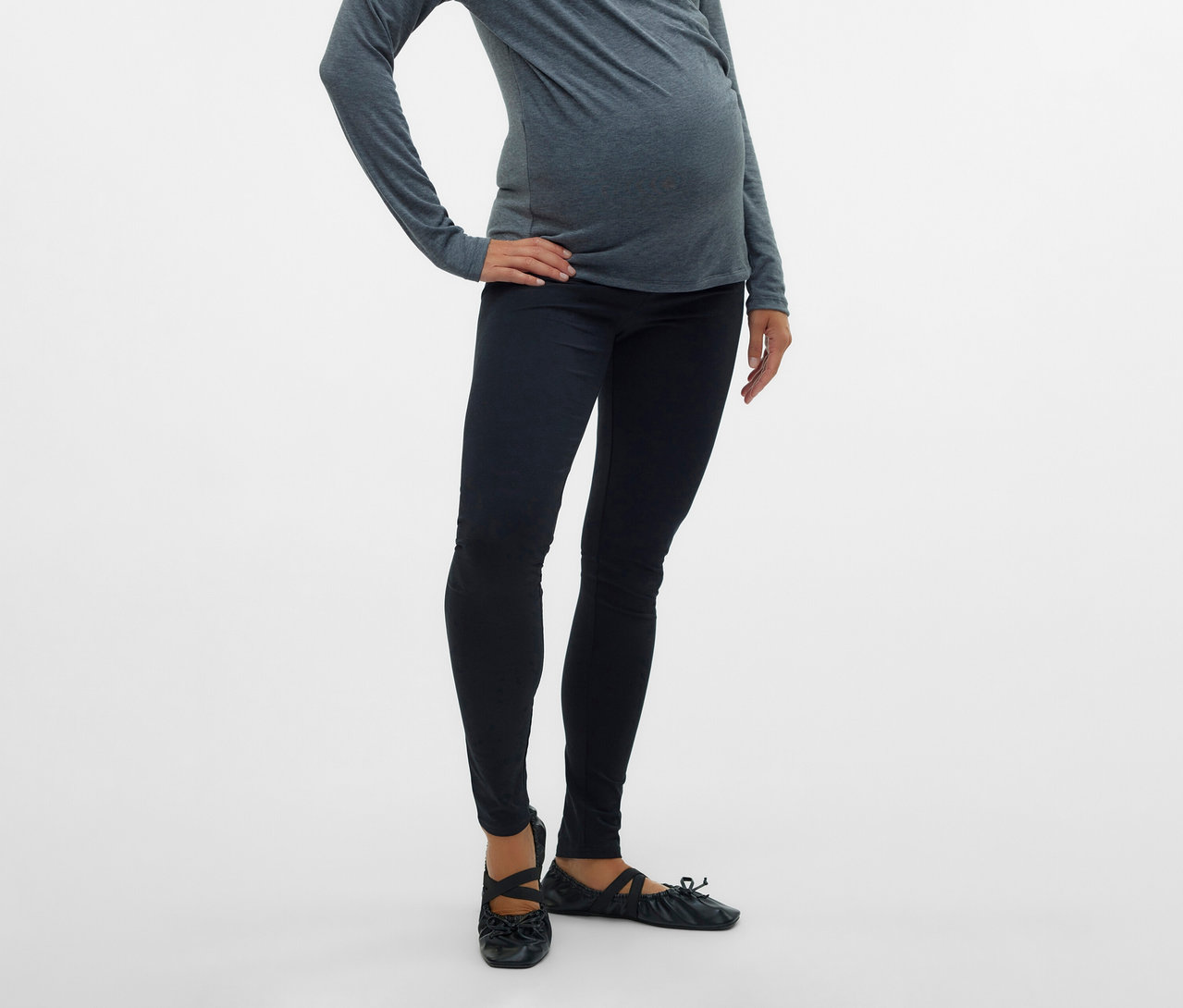 Femme enceinte portant un haut gris et un lot de 2 leggings MAMALICIOUS «
MLEMMA
» posant, la main sur la hanche, devant un fond blanc.