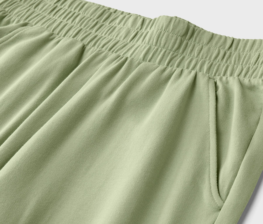 Gros plan de la taille d'un pantalon vert clair avec une taille élastique et une poche latérale.