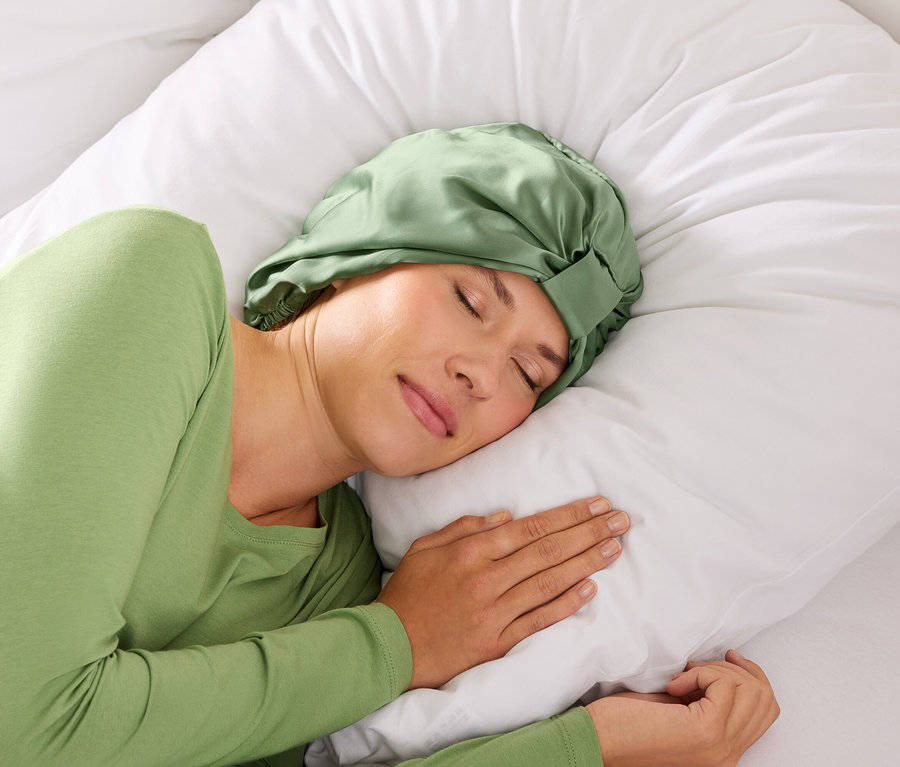 Femme dormant avec un bandeau vert sur un oreiller blanc.