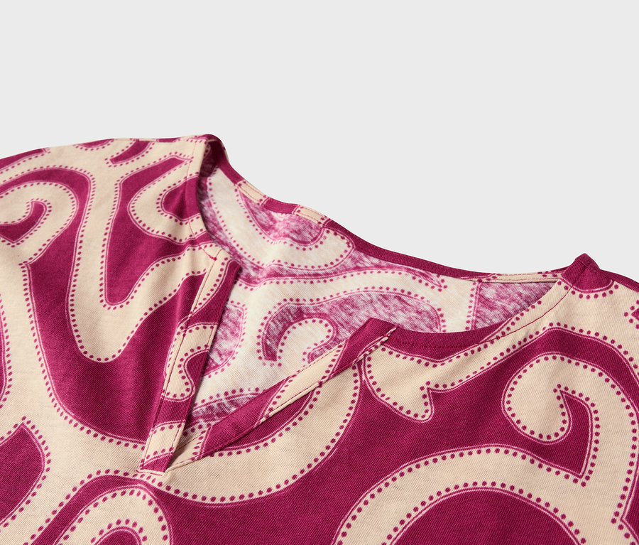 Gros plan d'un haut à col en V avec un motif abstrait magenta et beige.