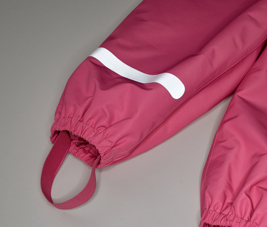 Gros plan d'une combinaison rose avec une bande réfléchissante blanche sur la manche et une bande élastique au pied.