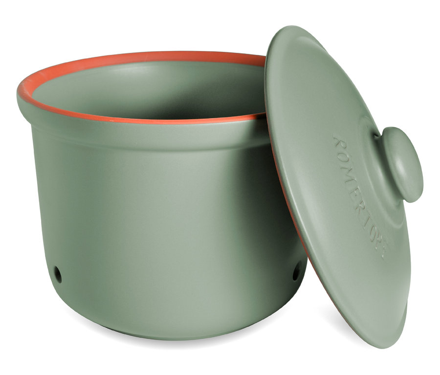 Un Römertopf vert avec un bord orange et un couvercle est posé sur une surface blanche.