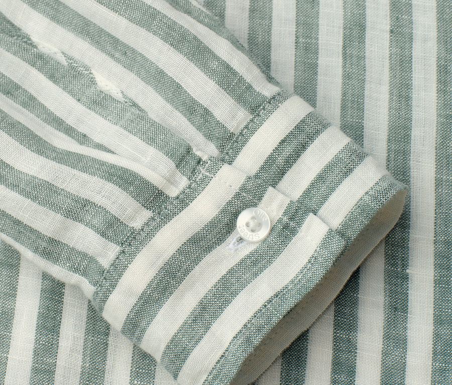 Gros plan sur la manche d'une chemise rayée verte et blanche avec un bouton blanc.
