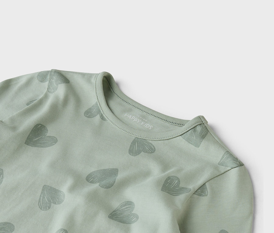 Gros plan d'un haut à manches longues vert clair avec un motif de cœurs gris.