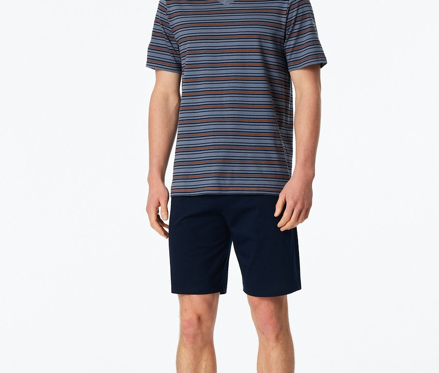 Homme debout pieds nus portant un t-shirt rayé bleu et un short bleu marine.