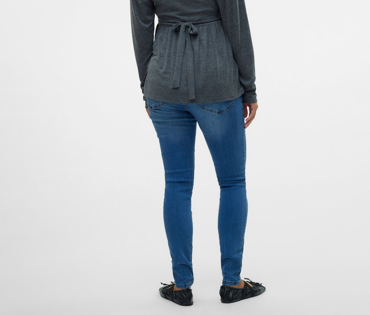 Vue de dos d'une femme portant un chemisier cache-cœur gris et un jean skinny MAMALICIOUS «
MLMILA » sur fond blanc.