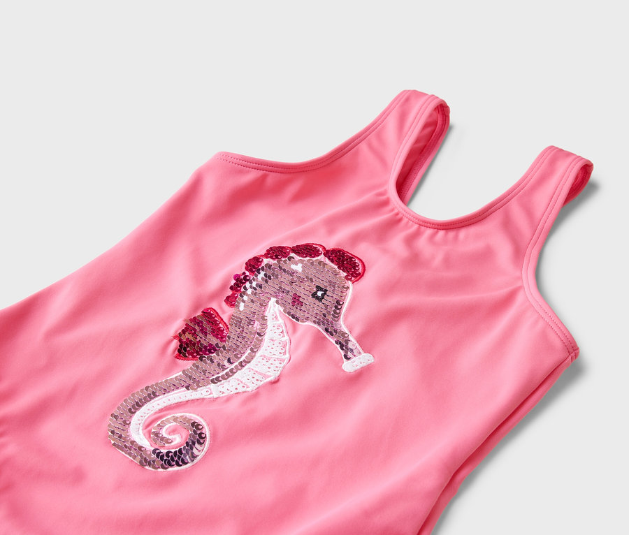Gros plan d'un maillot de bain rose avec un motif d'hippocampe à paillettes.